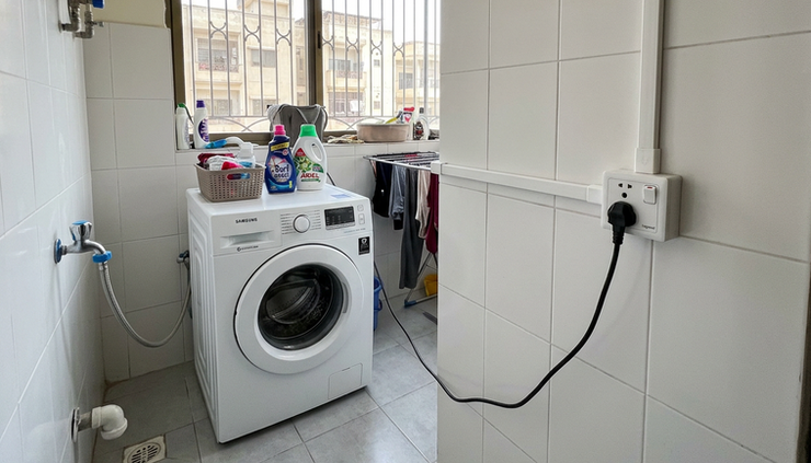 Wide-angle view of a compact Lahore laundry corner with neat conduit and a separate washing machine point.