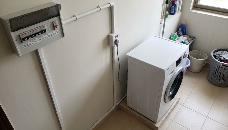 Overhead view of a neat washing machine electrical point with labelled breaker and safe conduit routing.