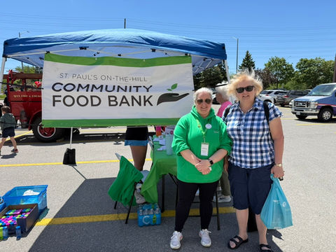 Donna Edwards & her daughter are standing with the Director of the St Paul's on the Hill Food Bank in a parking lot fundraiser.