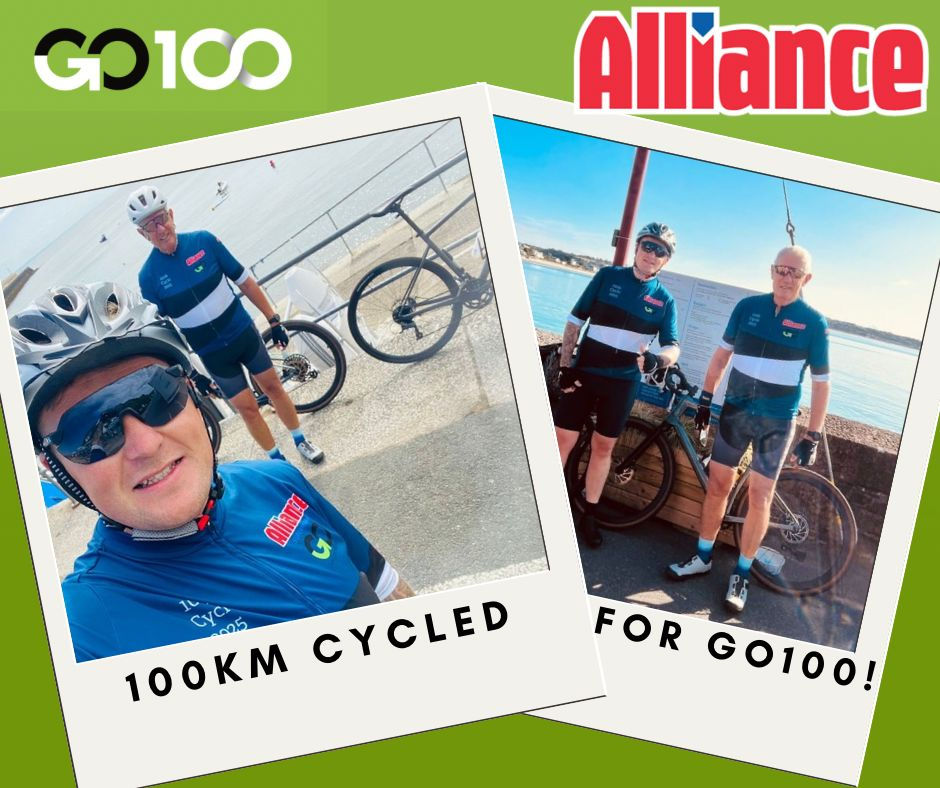 Cyclists in blue jerseys pose near a railing by the sea, celebrating a 100km ride for GO100. Green background with "Alliance" text visible.