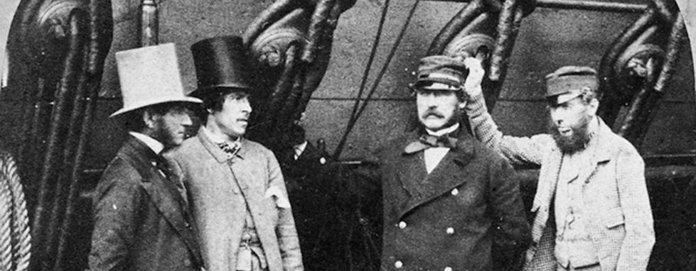 Photo of sailors standing next to ship's rigging.