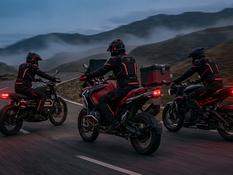 A group of three motorcyclists riding in unison on a winding mountain road at twilight, showcasing a sleek red and black aesthetic and community brotherhood.