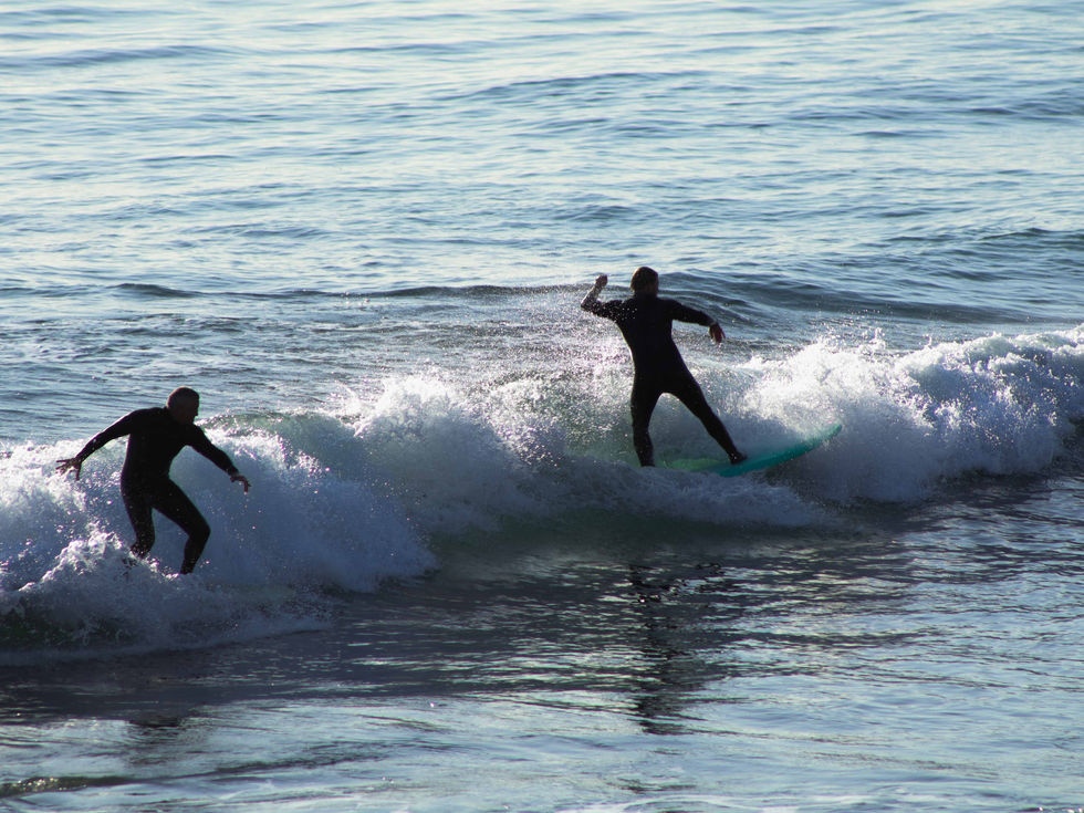 Two people surfing wave right next to each other