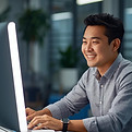 person in an office setting with bright lighting looking at her computer screen and smilin
