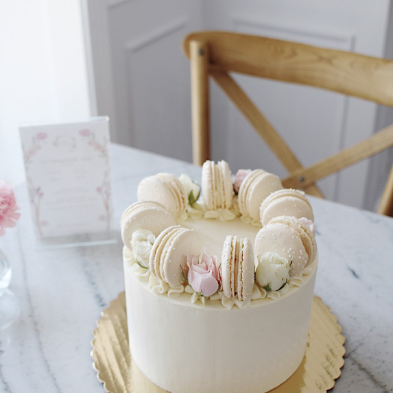 white cake with flowers and macarons