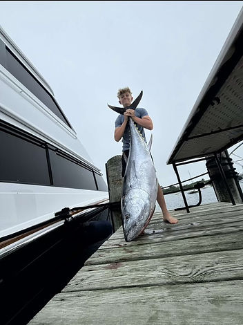 Angler aboard luxury yacht Barbaric proudly holding freshly caught tuna after an offshore fishing charter.