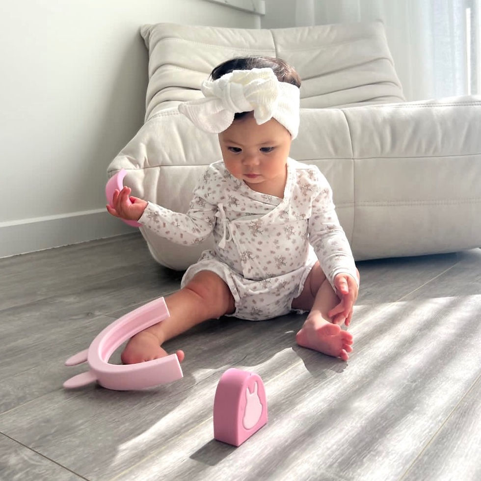 Thumbnail: baby girl playing on the floor with my pure pink silicone stacking toy bunny stackables