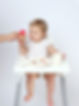 baby girl in white clothes eating ice cream made of watermelon
