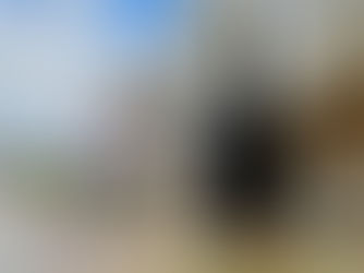 Sculpture of reflective spheres by a modern building, surrounded by red discs in water. Bridge visible in background under a blue sky.