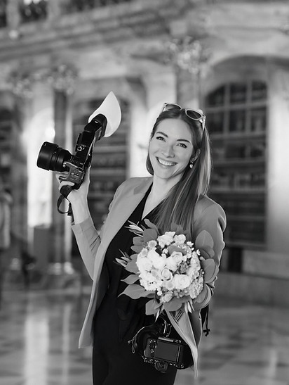 Portrait von Raluca Wassmus bei der Arbeit als Fotografin, die Kamera in einer Hand, der Brautstrauß in die andere Hand