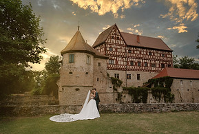 Brautpaar küsst sich vor der Schlosskulisse im Sonnenuntergang, fotografiert von Raluca Wassmus im Wasserschloss Unsleben
