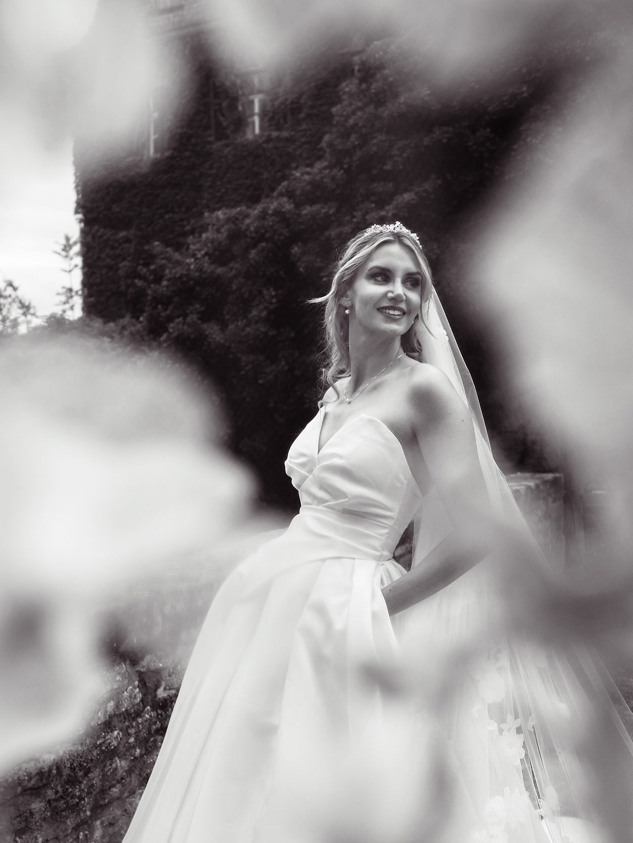 Schwarz-Weiß-Porträt einer Braut, die seitlich durch den Schleier blickt – Fine Art Hochzeitsfotografie mit emotionalem Ausdruck und weichem Licht