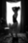 side profile of woman holding hair up in black lingerie and black platform heels standing