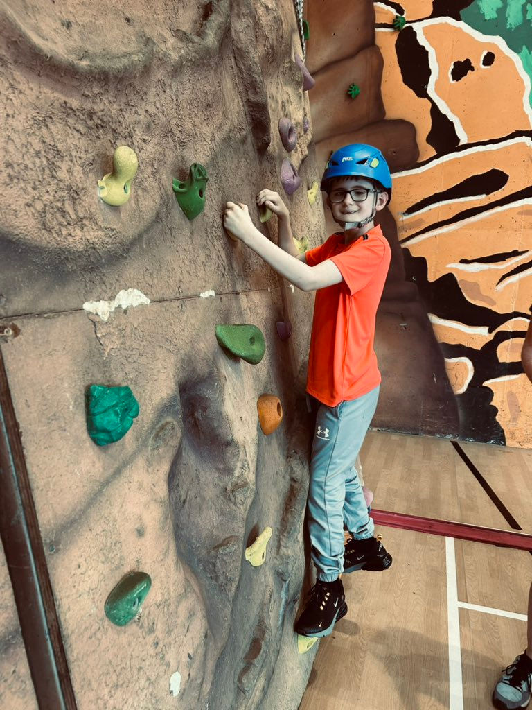 Image shows a pupil working their way up the climbing wall.