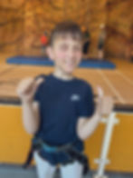 image shows pupil smiling with their thumbs up after successfully completing the climbing wall.