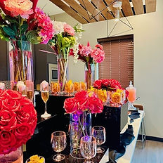 A beautifully styled tablescape featuring elevated floral risers, delicate floral arrangements, and refined event décor
