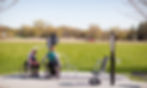 two wheelchair users using a accessible outdoor fitness area featuring fitness equipment from landscpae structures