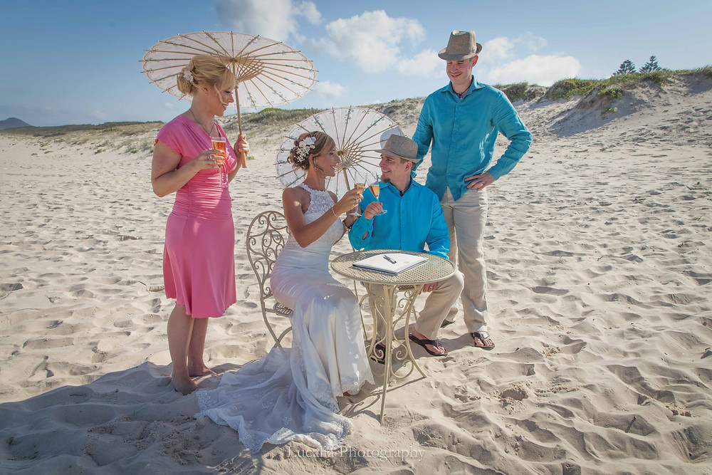 married couple after signing the marriage certificate on a beach with champagne