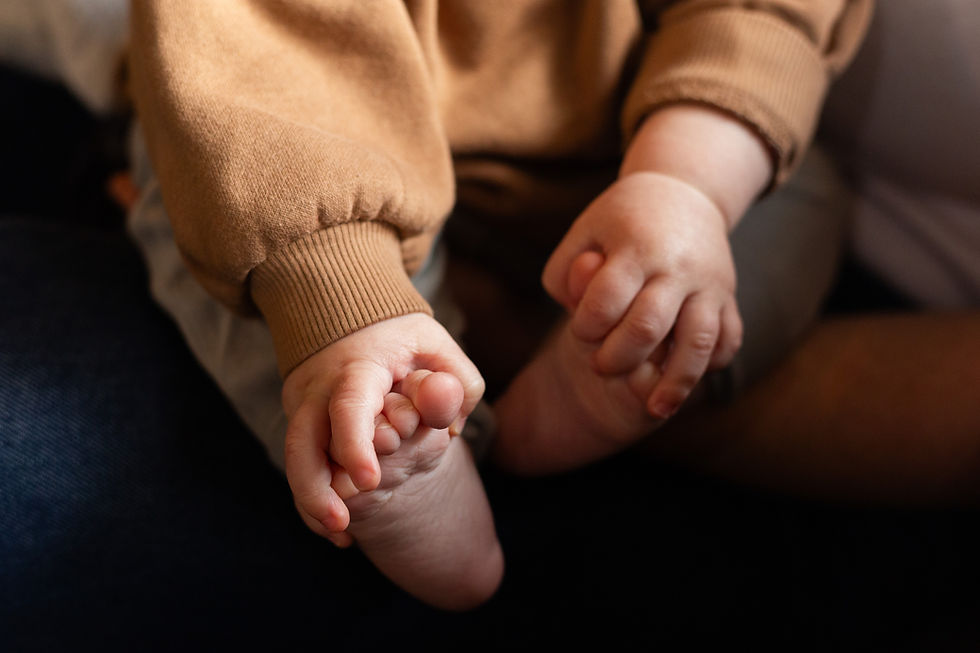a baby grasping his feet with his hands