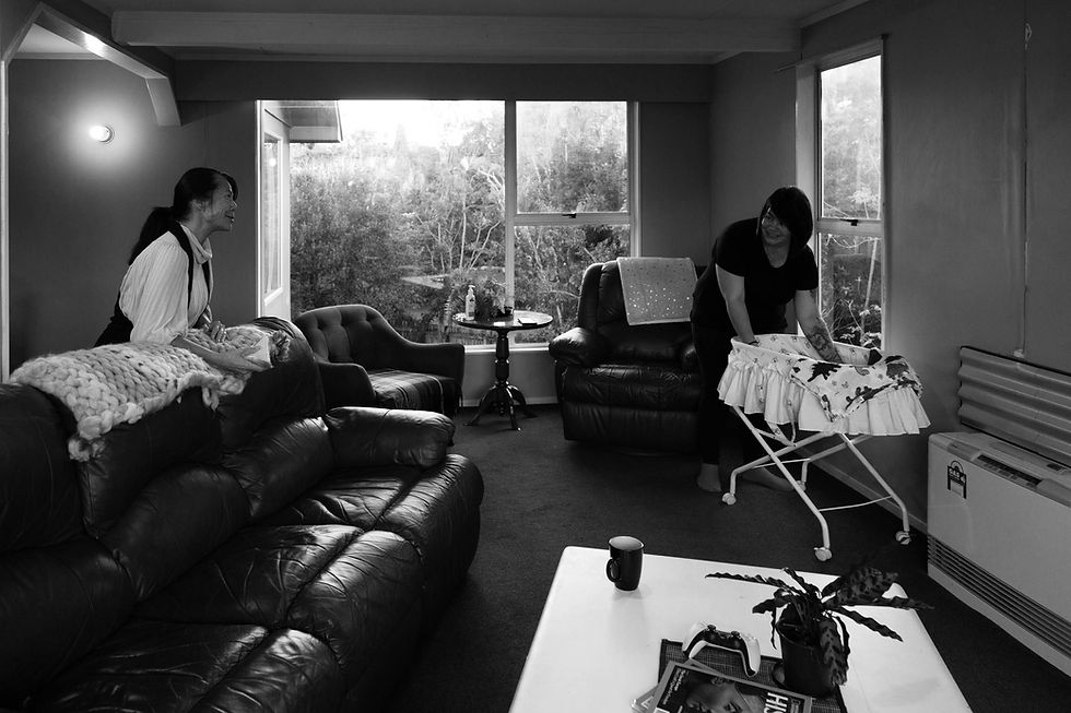 new mum is checking her newborn baby in bassinet whilst talking to her mum in the lounge room