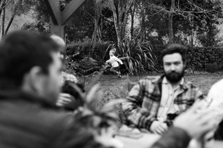 boy running in the background with adults chatting in the foreground Nelson family photographer
