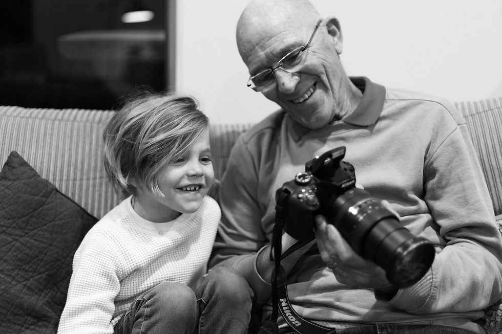 grandad showing his grandson photos of the back of a large camera