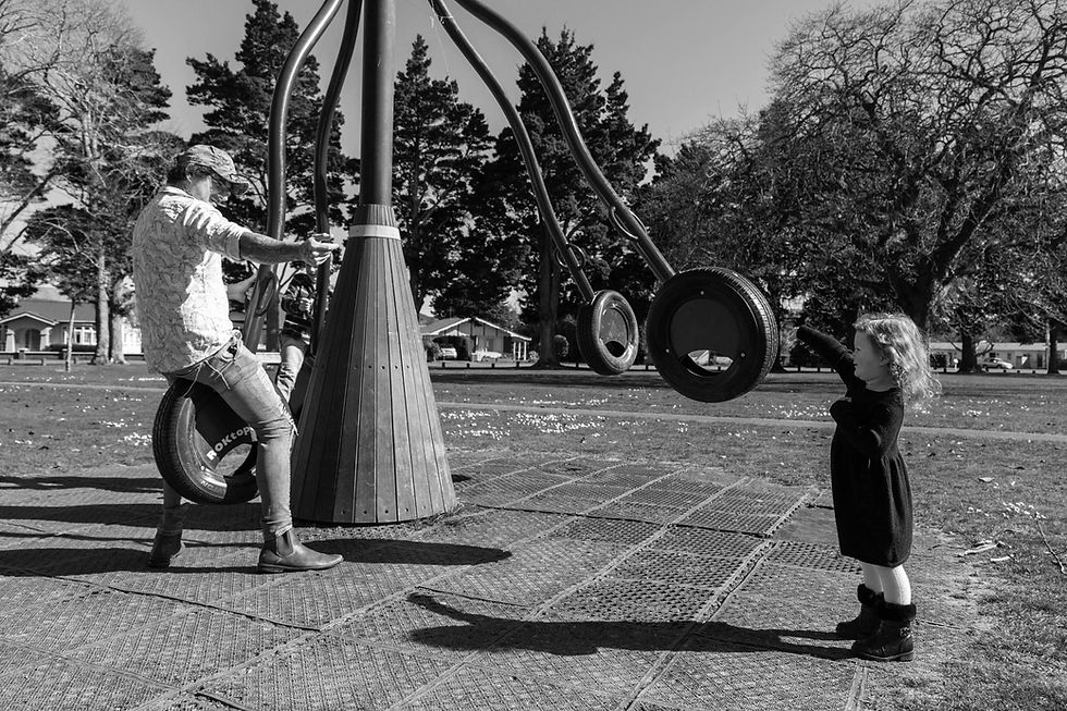 dad points to his daughter on tyre swing in the park