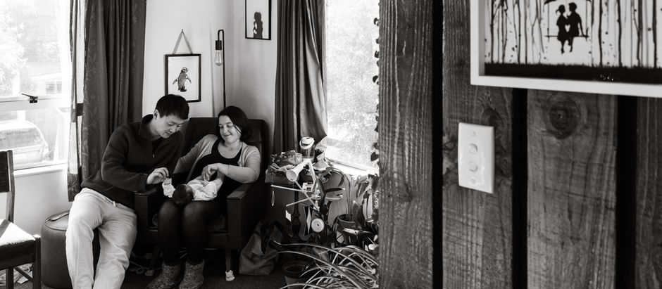 mum and dad sitting in their loungeroom with newborn baby surrounded by modern art