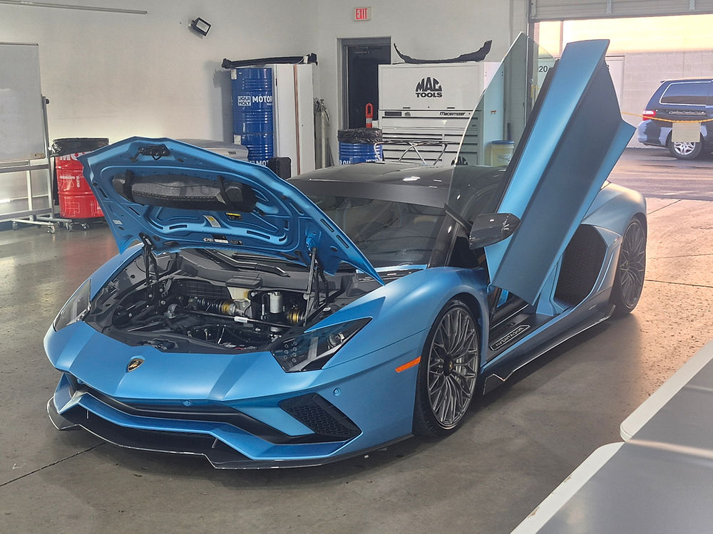 Blue Lamborghini with hood and doors open in a workshop