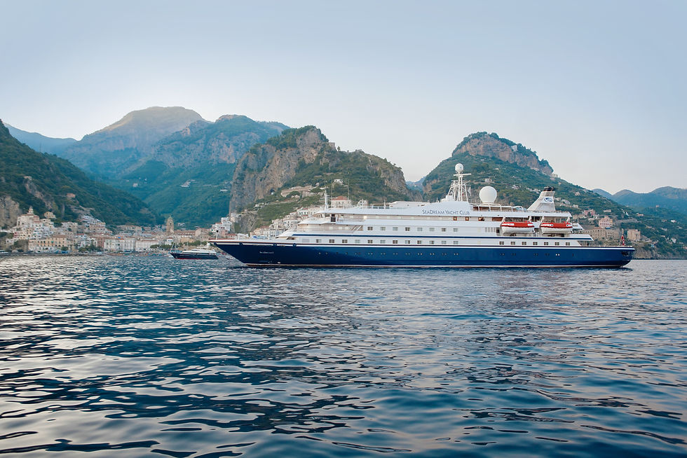 Luxury yacht sailing off the Amalfi Coast, with dramatic mountains and coastal towns in the background