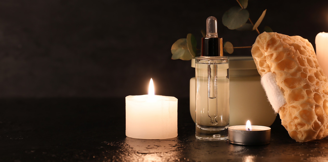 Composition with bath sponge, bottle of cosmetic product and burning candles on black back