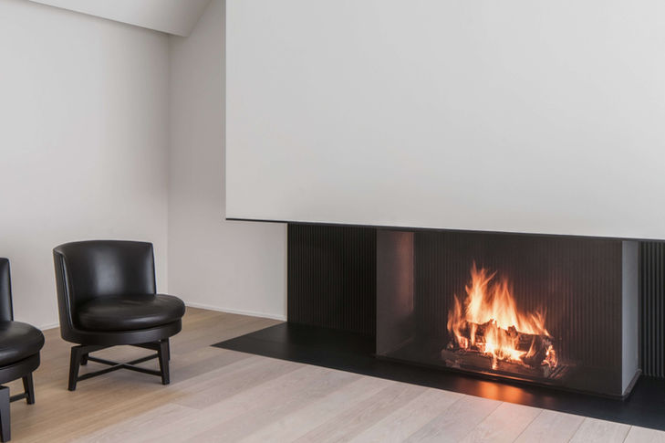 Floor-to-ceiling open fire with lowered spark guard in a modern and purist ambience.