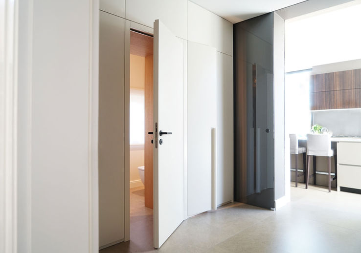 Weiße Schrankwand mit integrierter Badezimmertür.