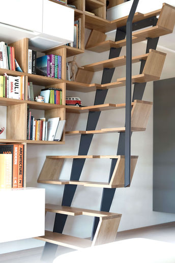 Stahl-Holz-Treppe, deren Stufen in die Bücherwand übergehen und zu Regalböden werden.