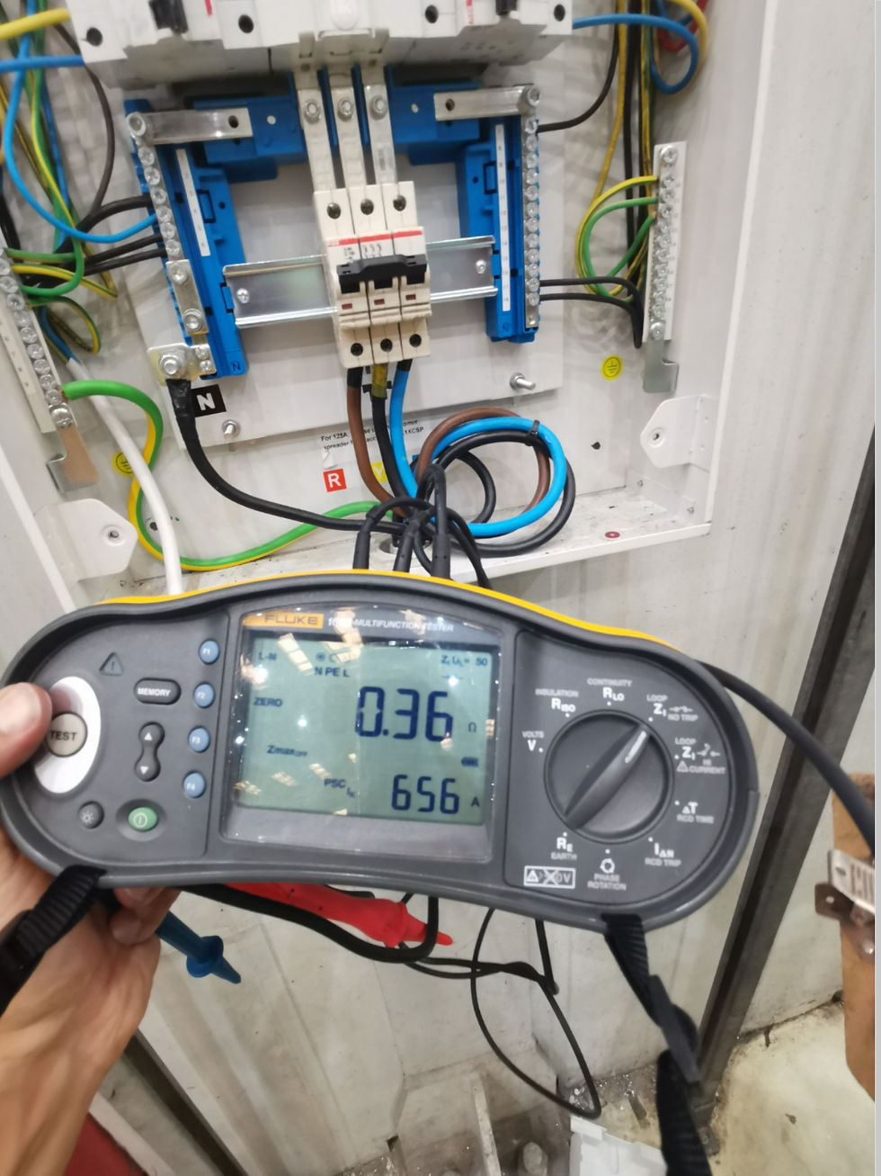 Eye-level view of an electrical panel with testing equipment connected