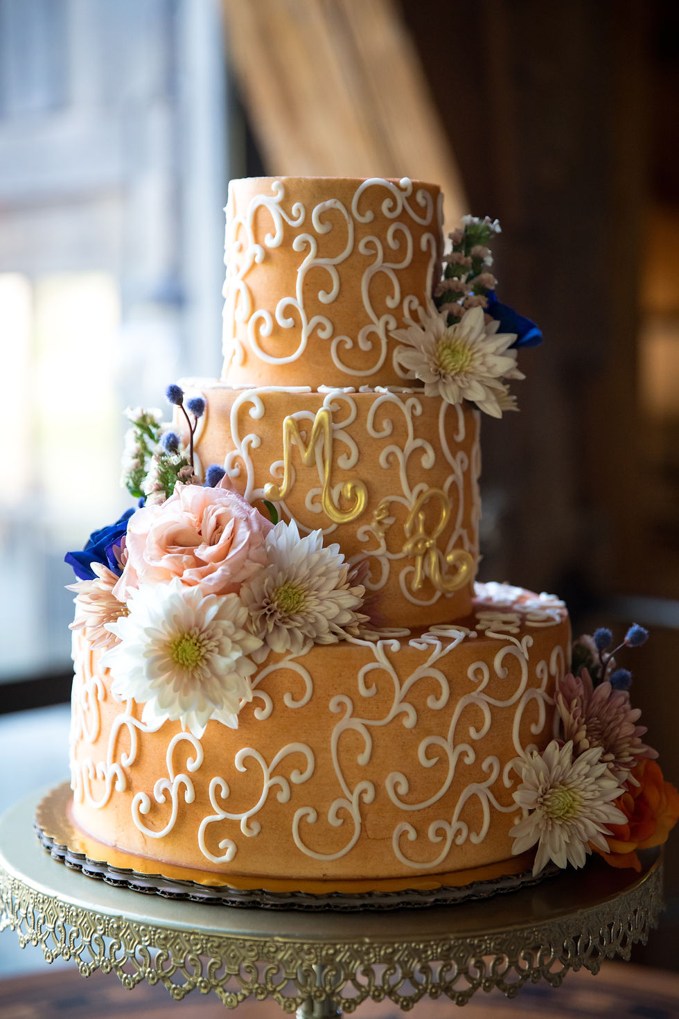 Wedding cake with florals, monogram, and swirls.