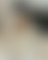 Woman wearing all white seat, writing in a journal on her bed