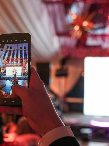 Male taking a picture on his phone of circus act.
