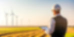 Agricultural engineer monitoring wind turbines and checking progress on digital tablet