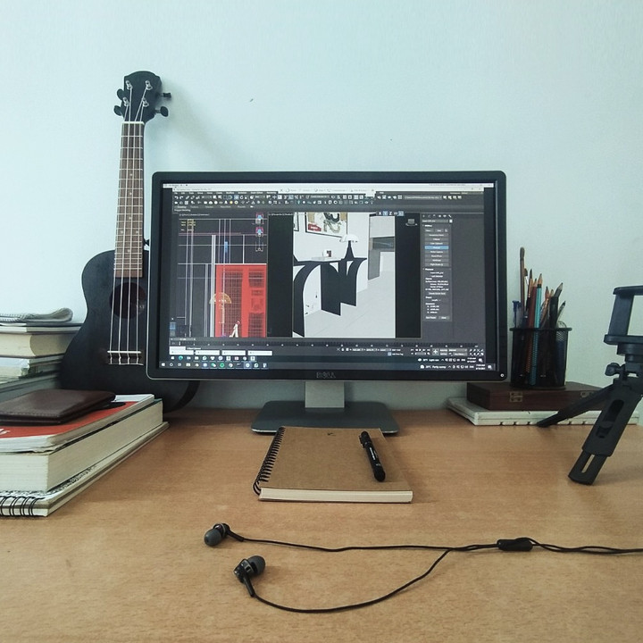 A computer, headphones, ukulele and books are on a desk