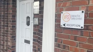 Brick building entrance with white door and signs for Rawa House and VFS Veteran Fire Safety Limited reception.