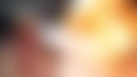 A person uses a red fire extinguisher to put out bright orange flames on a rough surface. White foam sprays onto the fire.