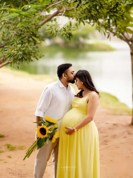 Expecting couple with sunflowers at an outdoor maternity shoot by a lake.
