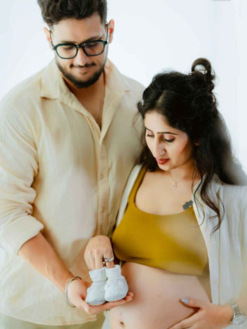 Expecting couple embracing during a casual indoor maternity session.