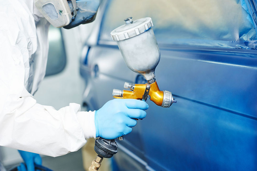 Man applying paint to a car panel using a spray gun