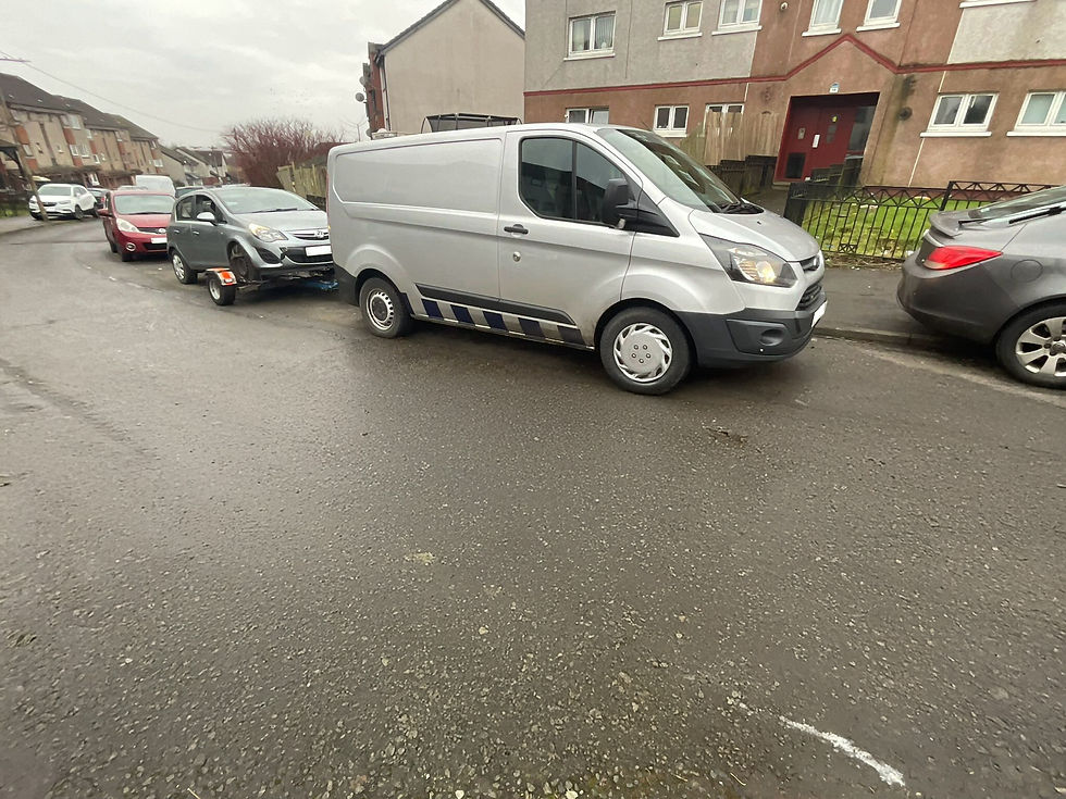 Silver recovery vehicle parked in front of a broken down car