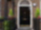 Black traditional composite front door with a gold knocker and letterbox set in a brick archway