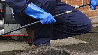 A man using a rod to clear a drain