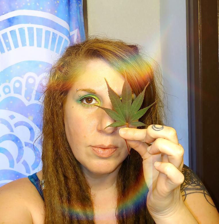 Genea a red haired girl with dreads with a fire maple leaf in front of one of her eyes with a periwinkle flowe mandal shower curtaion in the background