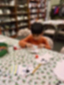 A child decorates paper crafts on a festive tablecloth at the Dunstable Public Library
